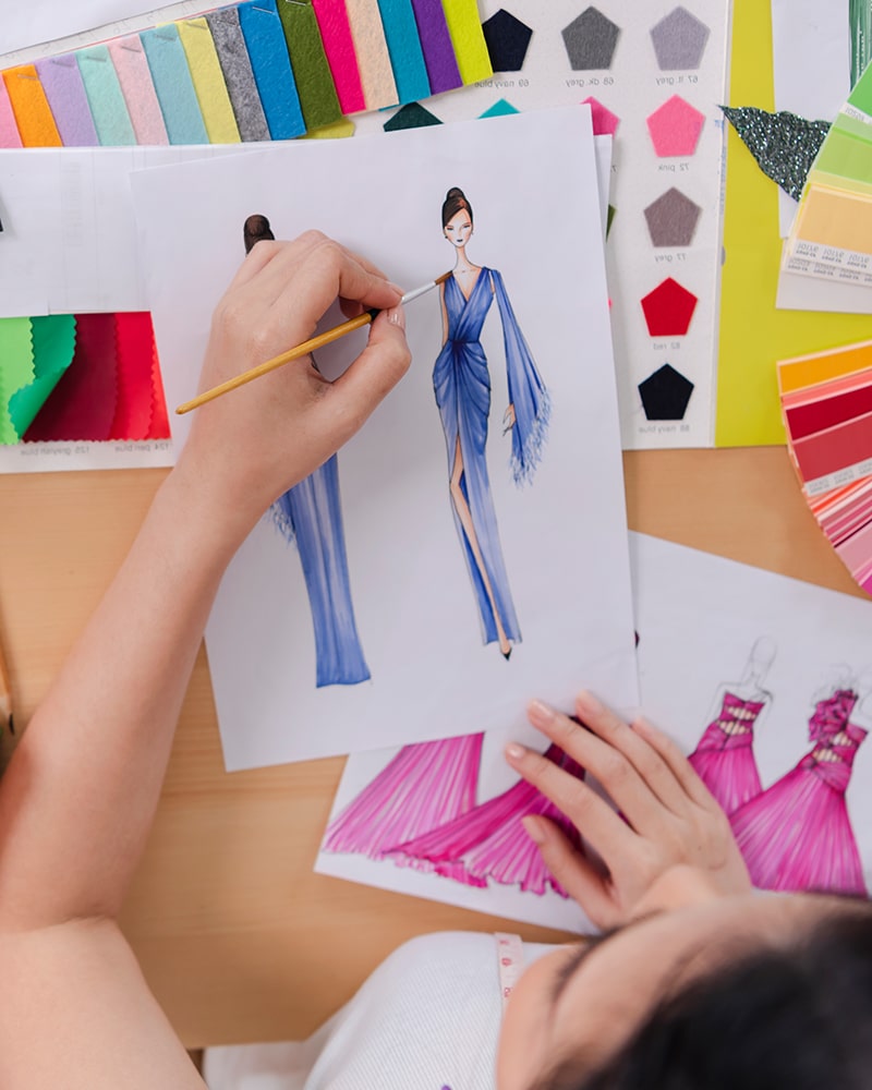 Top view on woman designer drawing clothes sketches